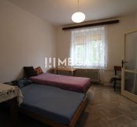A bedroom with light furniture and beds in a two-room apartment with a wooden decor floor.