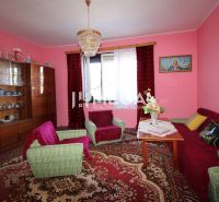 Living room with pink walls, a sofa set, a display cabinet, and a chandelier in a family house.