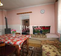 Interior of a family house with a kitchen table, stove, and bed, floor with wooden decor.