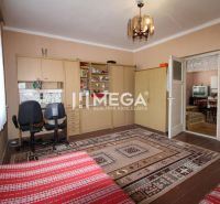 Interior of a family house with a carpet, a desk and chairs, and a door to another room.