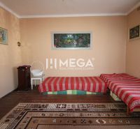 A room in a family house with carpets, beds, and a standing stove.