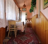 A hallway with a carpet runner, a table, curtains, and wood paneling in a family house.