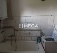 A bathroom in a family house with a bathtub and a washing machine, surrounded by white tiles.