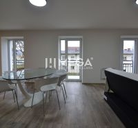 Dining area in a 3-room apartment with a wooden decor floor and a glass table.