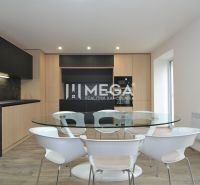 A kitchen in a 3-room apartment with a black kitchen unit, a round glass table, and a floor with a wooden decor.