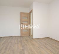 An empty room in a three-room apartment with a wood-patterned floor.
