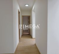 A hallway with white walls and a wooden decor floor in a 2-room apartment.