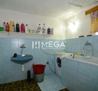 A bathroom in a family house with a bathtub, sink, and washing machine, with cleaning products on display.