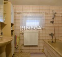 A bathroom in a family house with beige tiles, a bathtub, and a sink.