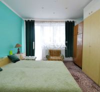 A bedroom in a family house with a turquoise wall, a large bed, and wardrobes.