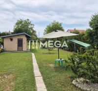 The garden of a family house in Lackovce with a lawn, seating area, and a small structure.