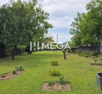 Garden space of a family house in Lackovce with lawn and trees.