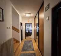 The hallway of a family house with a wooden decor floor and cream walls.
