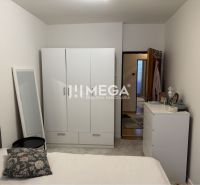 A bright bedroom in a family house with white furniture and a mirror leaning against the wall.