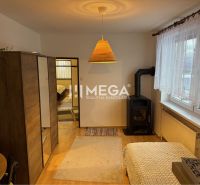 A room in a family house with a tiled stove, wooden decor, carpet, large window.