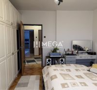 A bedroom in a family house with a white wardrobe and a decorative table behind the bed.