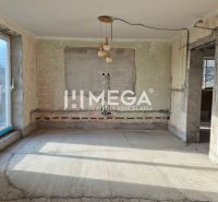 An unfurnished room in a family house with a concrete floor and balcony doors.