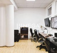 An office with a wooden decor floor, desks, chairs, and screens on the wall.