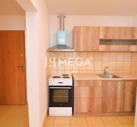 A kitchen in a 2-room apartment with a stove, extractor hood, and cabinets with a wooden decor.