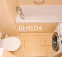 Bathroom with a bathtub, washing machine, and toilet in a 2-room apartment with tiles.