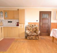 A kitchen in a family house with a wooden-patterned floor, a wooden cabinet, and a chair.