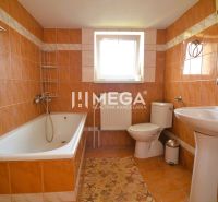 A bathroom in a family house with a bathtub, a sink, and orange tiles.