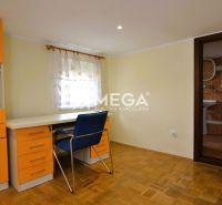 A room in a family house with orange furniture and a wood-patterned floor.