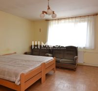 Bedroom with a bed, sofa, and wooden decor flooring in a family house.
