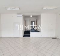 Commercial space with white walls and tiles, stairs lead to a higher level.
