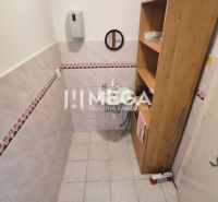 Bathroom in commercial premises with a sink, shelves, and tiled walls.