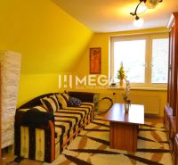 A room in a family house with yellow walls, a sofa, and wooden decor.
