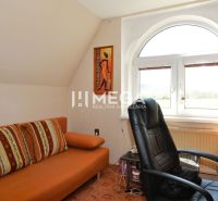 A study in a family house with an orange sofa, an armchair, and a view from the window.