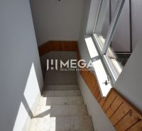 A staircase with wooden paneling and a large window in a 2-room apartment.