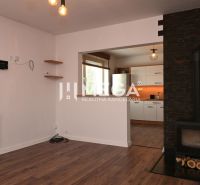 Interior of a family house with a fireplace, wooden decor flooring, and a view into the kitchen.