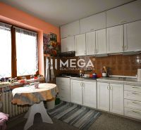 A kitchen in a family house with white cabinets and floral decorations on the wall.