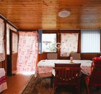 Interior of a family house with a wooden ceiling, sofa set, table, and decorative curtains.