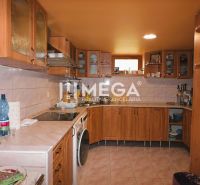 A kitchen in a family house with wooden cabinets and ceramic tiles on the walls.