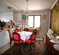 A dining room in a family house with vintage furniture, a large wallpaper, and decorations on wooden cabinets.