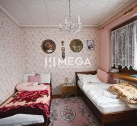 Two beds with pictures of saints on the walls in a family house.