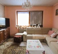 Living room in a family house with a corner sofa, carpet, and a television on a cabinet.