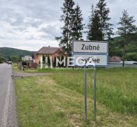 A landscape in Zubné with a road and green residential plots.