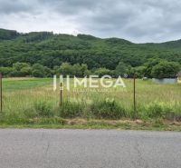 Lands - housing in Zubné, green meadows, fencing, car by the road, wooded hills.