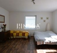 Bedroom in a family house with a bed, cabinet, and wooden decor flooring.