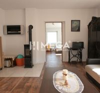 Living room in a family house with tiled stove and wood-patterned flooring.