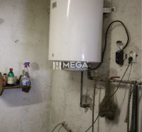 A boiler in the utility room of a family house with wall-mounted tanks.