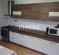 A kitchen in a family house with a wooden decor, a cooktop, a microwave, a fan.