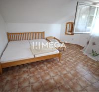 Bedroom in a family house with ceramic tiles, a bed, and an open window.