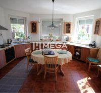 A kitchen in a family house with wooden decor, a dining table, and a tiled floor.