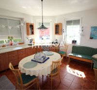 Dining room in a family house with a round table, chairs, a sofa, and decorations.