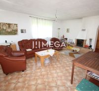 Living room in a family house with a fireplace, leather sofa, and paintings on the walls.